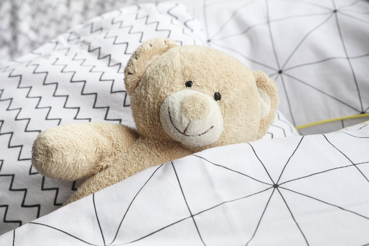 A cuddly teddy bear snuggled in graphic print bedding creates a cheerful and comforting scene.